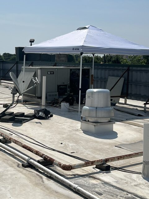 Rooftop unit opened for service with a shade canopy set up over it
