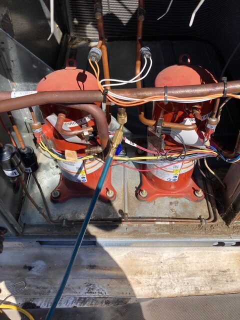 Twin compressors and refrigerant piping inside a rooftop unit
